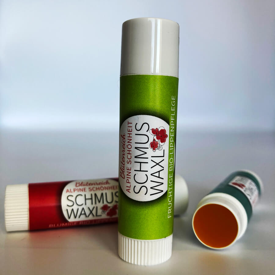 Drei Bio Lippenbalsam fruchtig in Front, rosa liegend, blau liegend und geöffnet